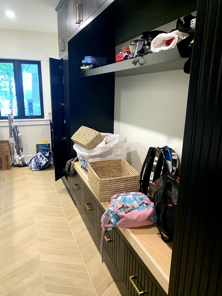 Black mudroom built-ins with backpacks and woven baskets landing on the bench after school