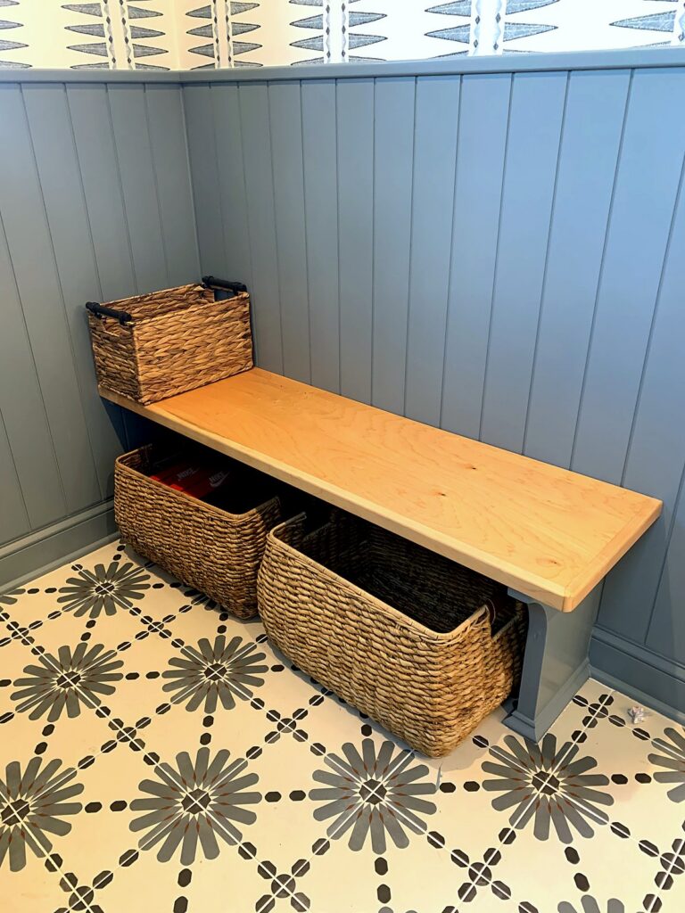 Wood mudroom bench with wicker shoe baskets tucked underneath for easy kid access