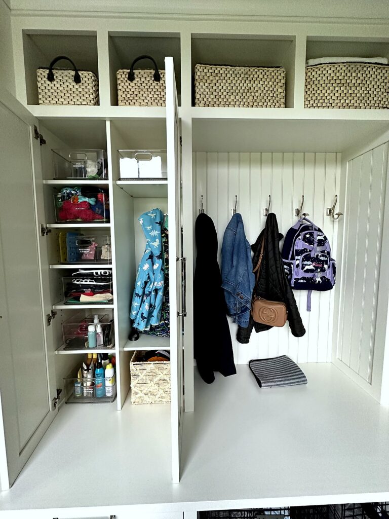 Organized mudroom cabinet with shelves of kids' gear next to hanging coats and backpacks