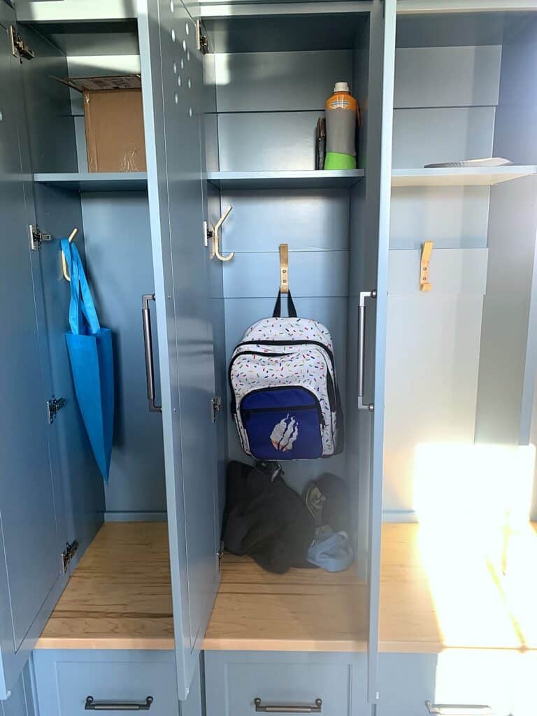 Open mudroom locker with a backpack hanging from a hook above the bench cubby