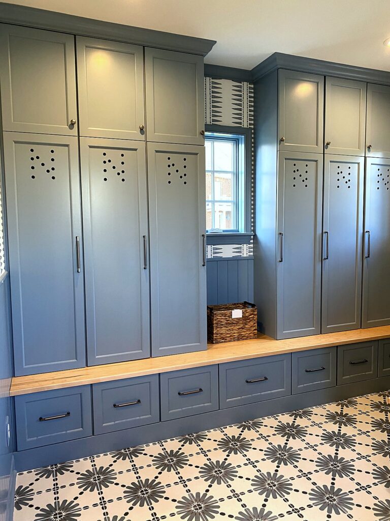 Styled mudroom locker wall with bench, storage drawers, and a wicker basket after organization