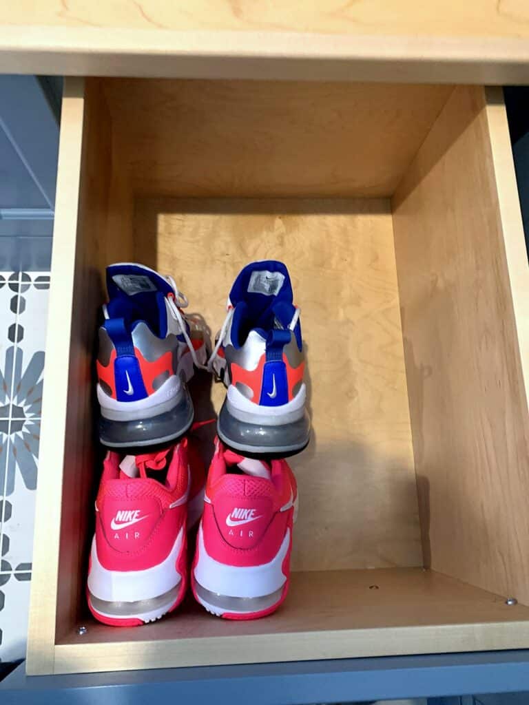 Kids' sneakers stored in a pull-out mudroom shoe drawer under the bench