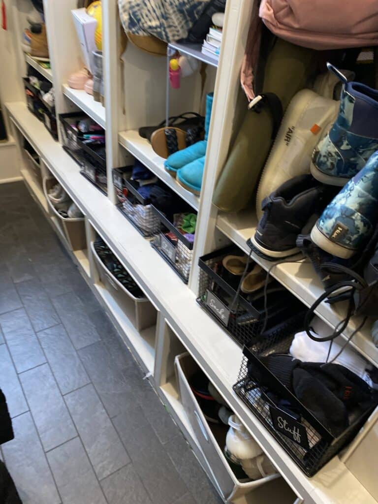 Kids' shoes and boots organized on low mudroom shelves with pull-out wire baskets