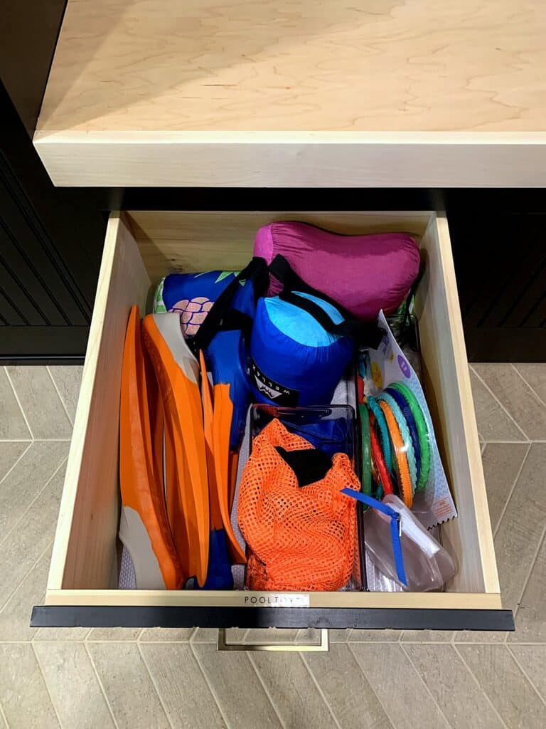 Pool gear and swim accessories stored in a labeled pull-out drawer in the mudroom