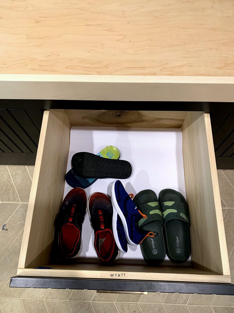 Each child's everyday shoes stored in their own labeled pull-out drawer in the mudroom