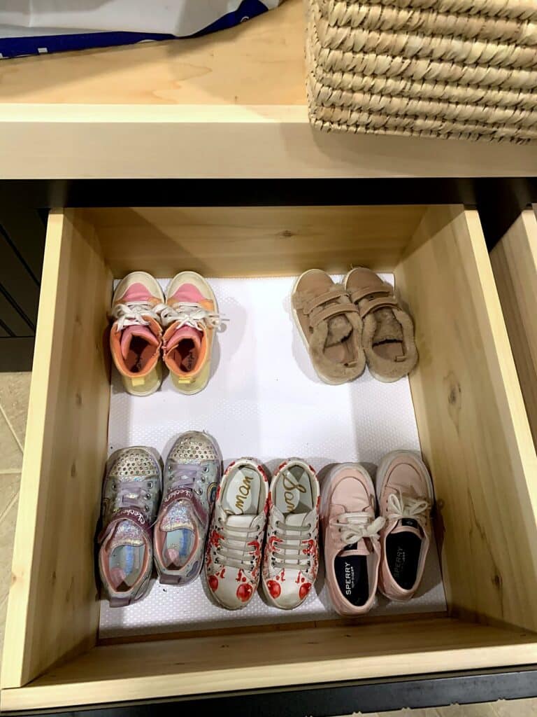 Toddler shoes lined up in a pull-out shoe drawer of the mudroom drop zone