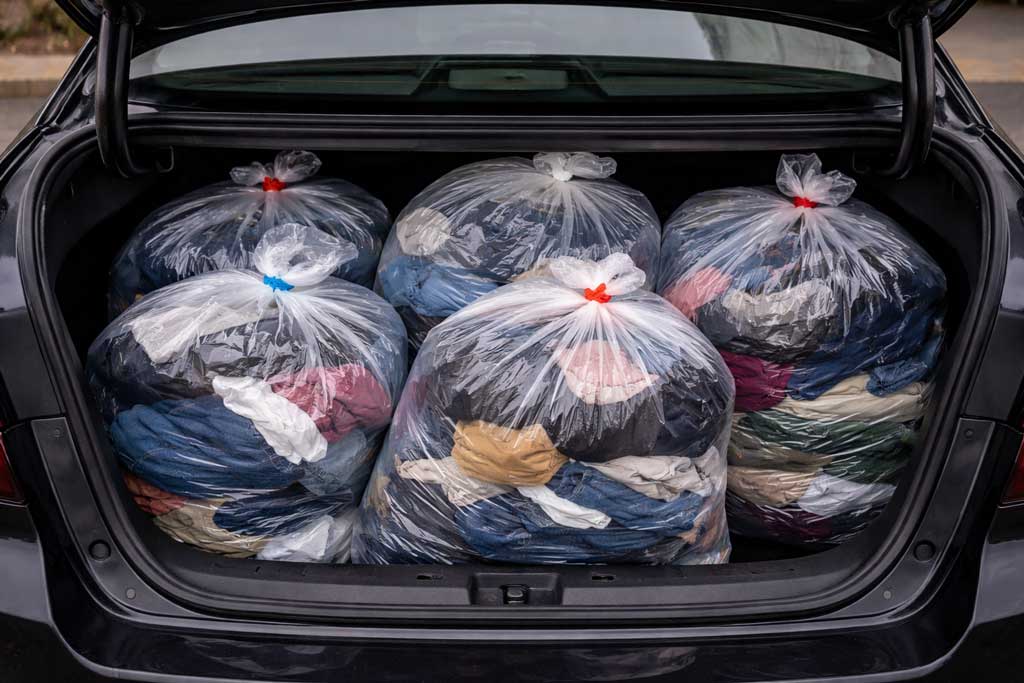 Car trunk full of bags of clothing ready to donate after decluttering