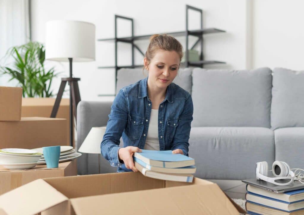 Woman unpacking a box of books after moving