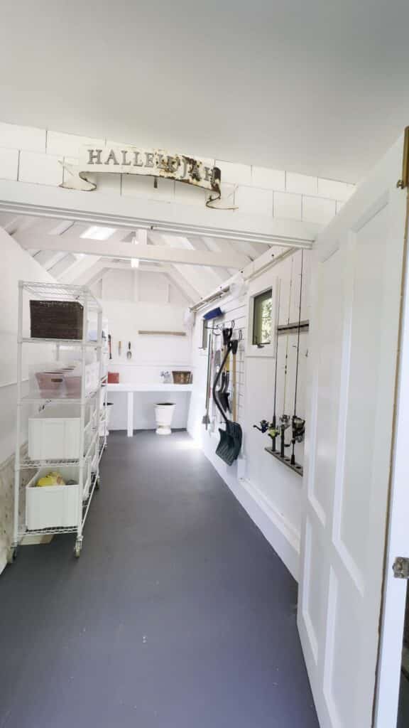 Fully organized Annapolis backyard shed after professional home organization, with rolling shelves, slat wall, workbench, and Hallelujah sign above the door