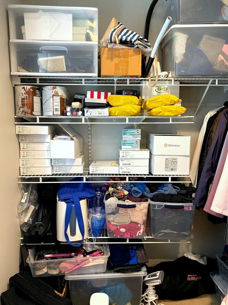 Disorganized closet shelving packed with medical supplies, Bioness boxes, and miscellaneous items before professional organization