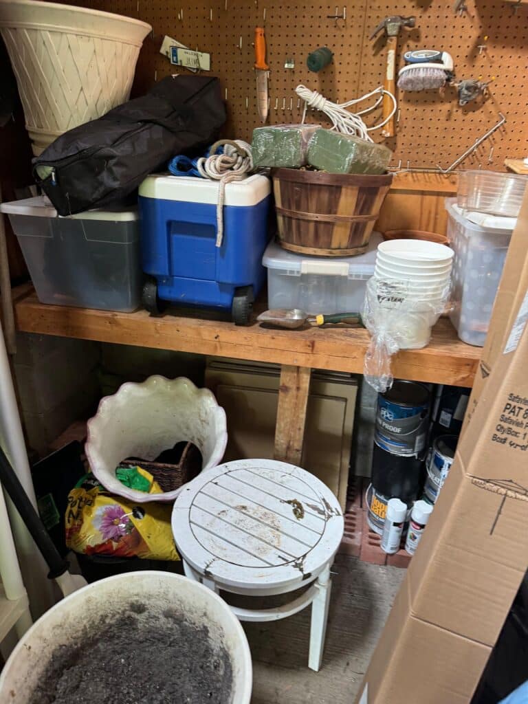 Cluttered shed workbench area with tools and gardening supplies before professional organization