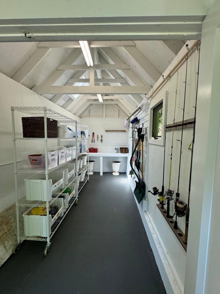 Organized backyard shed interior in Annapolis showing rolling white wire shelves and fishing rod wall storage