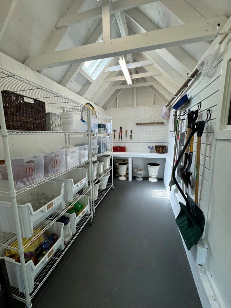 Organized Annapolis shed with rolling white shelves, clear and labeled bins, and dedicated storage zones throughout