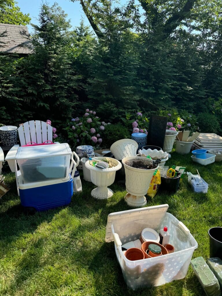 Gardening supplies and pots sorted on the lawn during shed declutter with Annapolis garden in the background