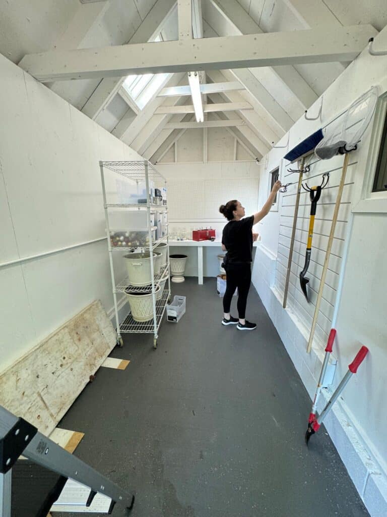 Professional organizer installing a slat wall in an Annapolis backyard shed