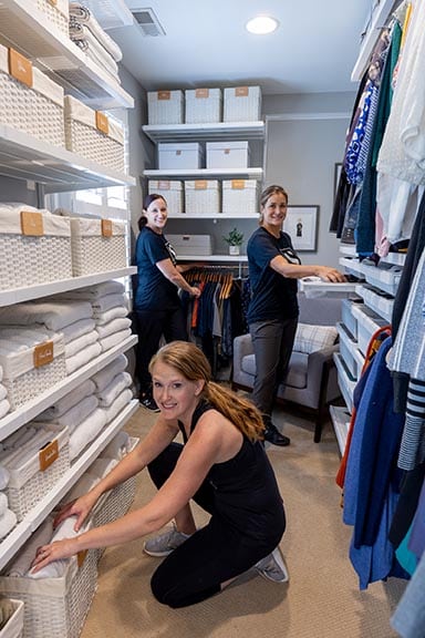 Three Systems by Susie team members in the fully organized walk-in closet showing linen shelving and accessible storage