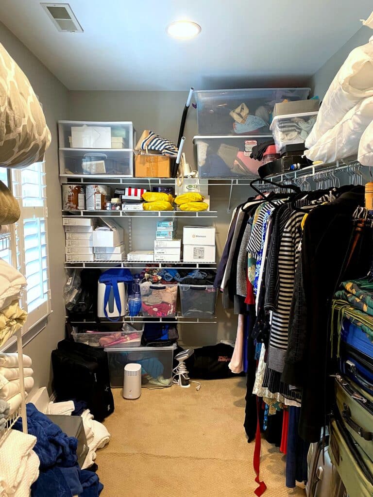 Wide view of cluttered walk-in closet before professional organization with overflowing shelves and medical supplies