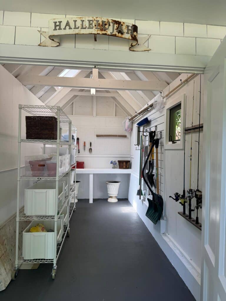 White interior of an organized Annapolis garden shed after professional organization with rolling shelves and slat wall