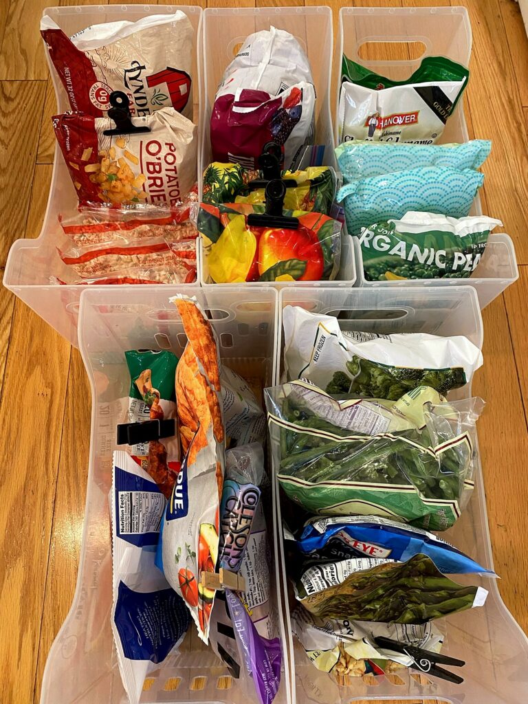 Container Store multipurpose bins on the floor being filled and sorted with frozen food during freezer organization