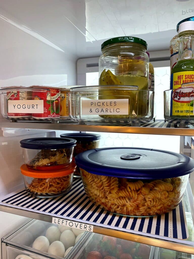 Refrigerator shelf with labeled yogurt, pickles, and salsas bins holding hot sauce and spreads