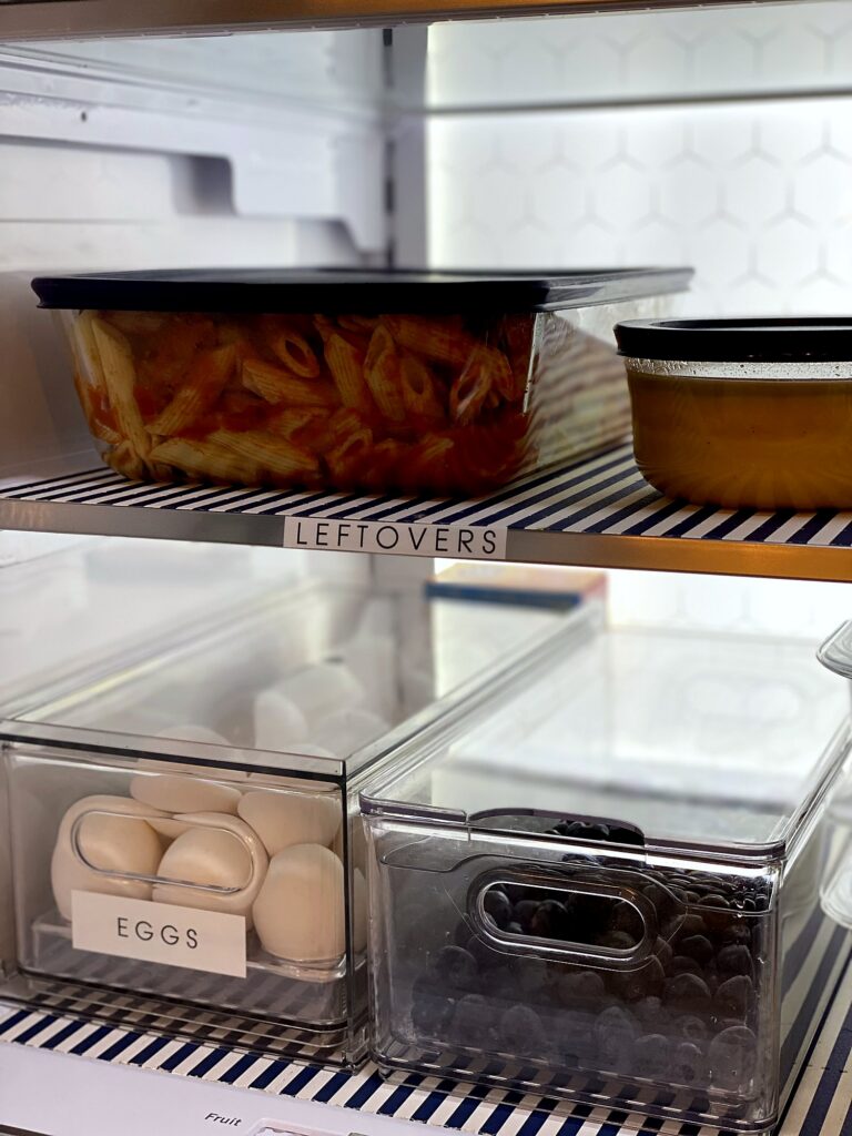 Refrigerator leftovers shelf with labeled Leftovers zone above clear egg and berry storage bins