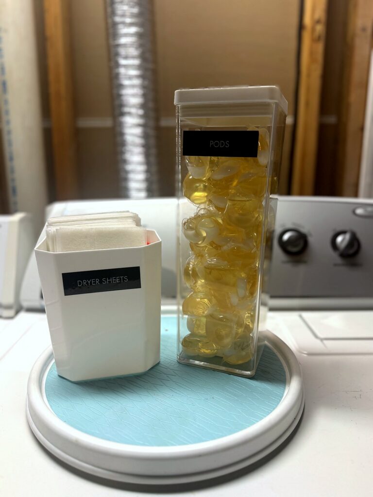 Lazy Susan on top of the washer holding decanted laundry pods and dryer sheets