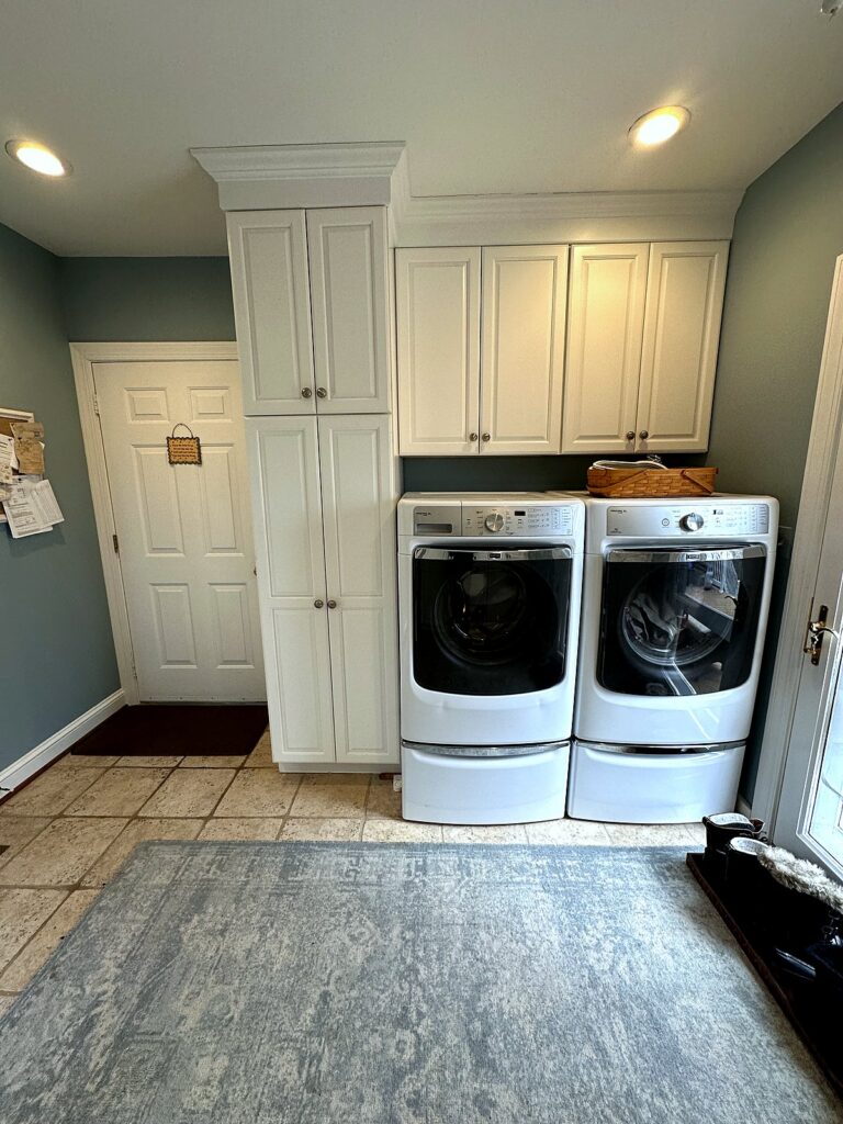 Organized laundry room with white cabinet wall and front-load washer and dryer after professional organizing in Annapolis
